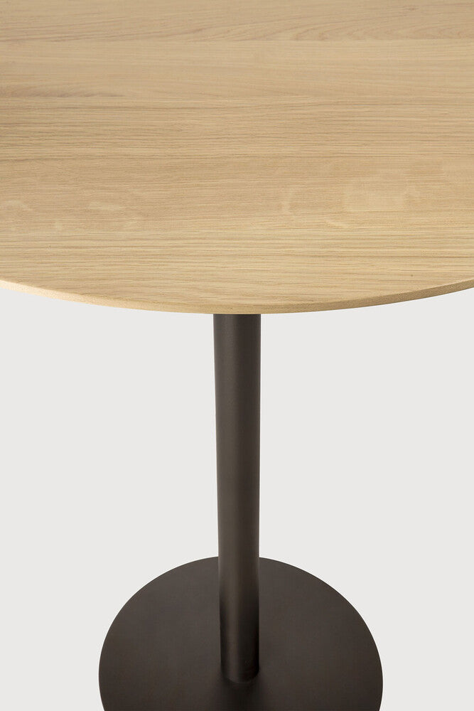 Detail of Ethnicraft Blend Bar Table showing the varnished solid oak top and Dark Bronze pedestal