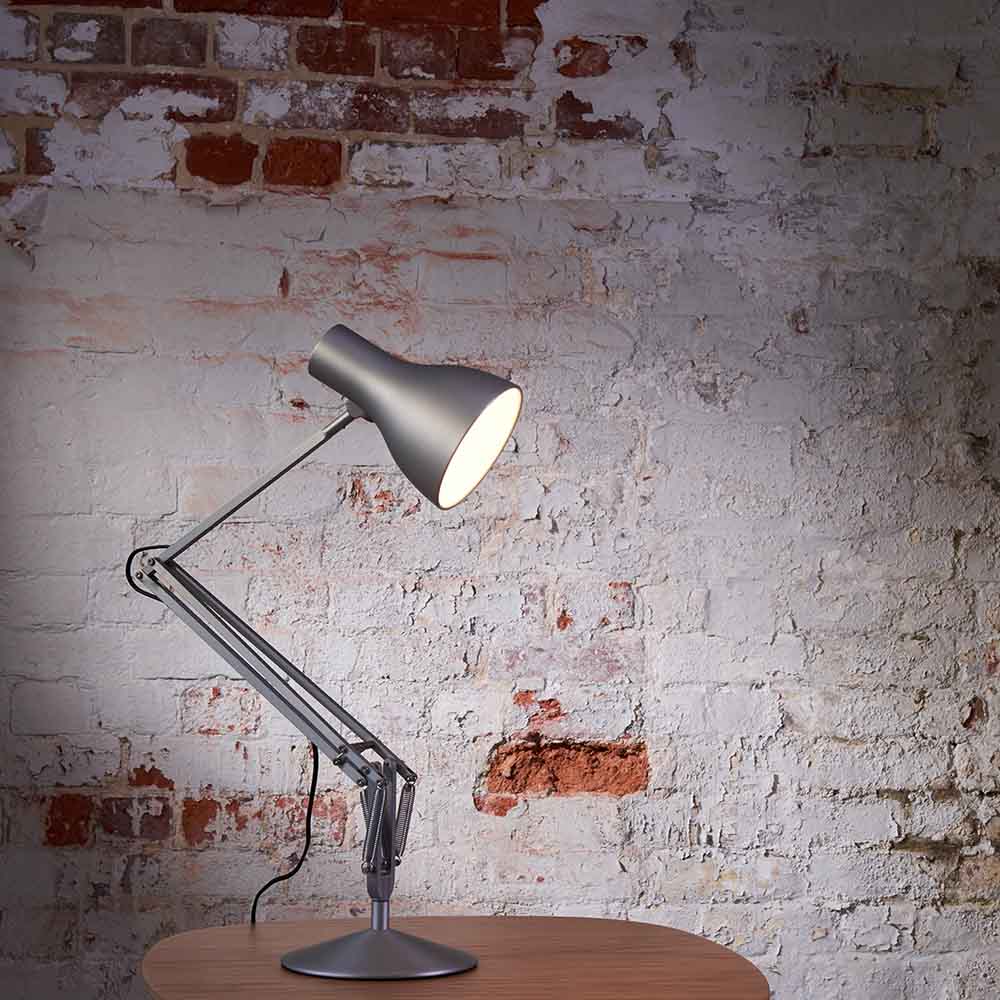 Anglepoise Type 75 desk lamp in Silver Lustre on a round table against a whitewashed brick wall