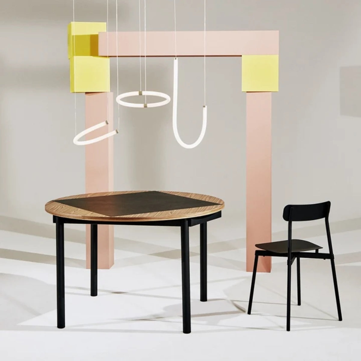 Petite Friture Unseen J pendant lights above a round dining table with black chairs