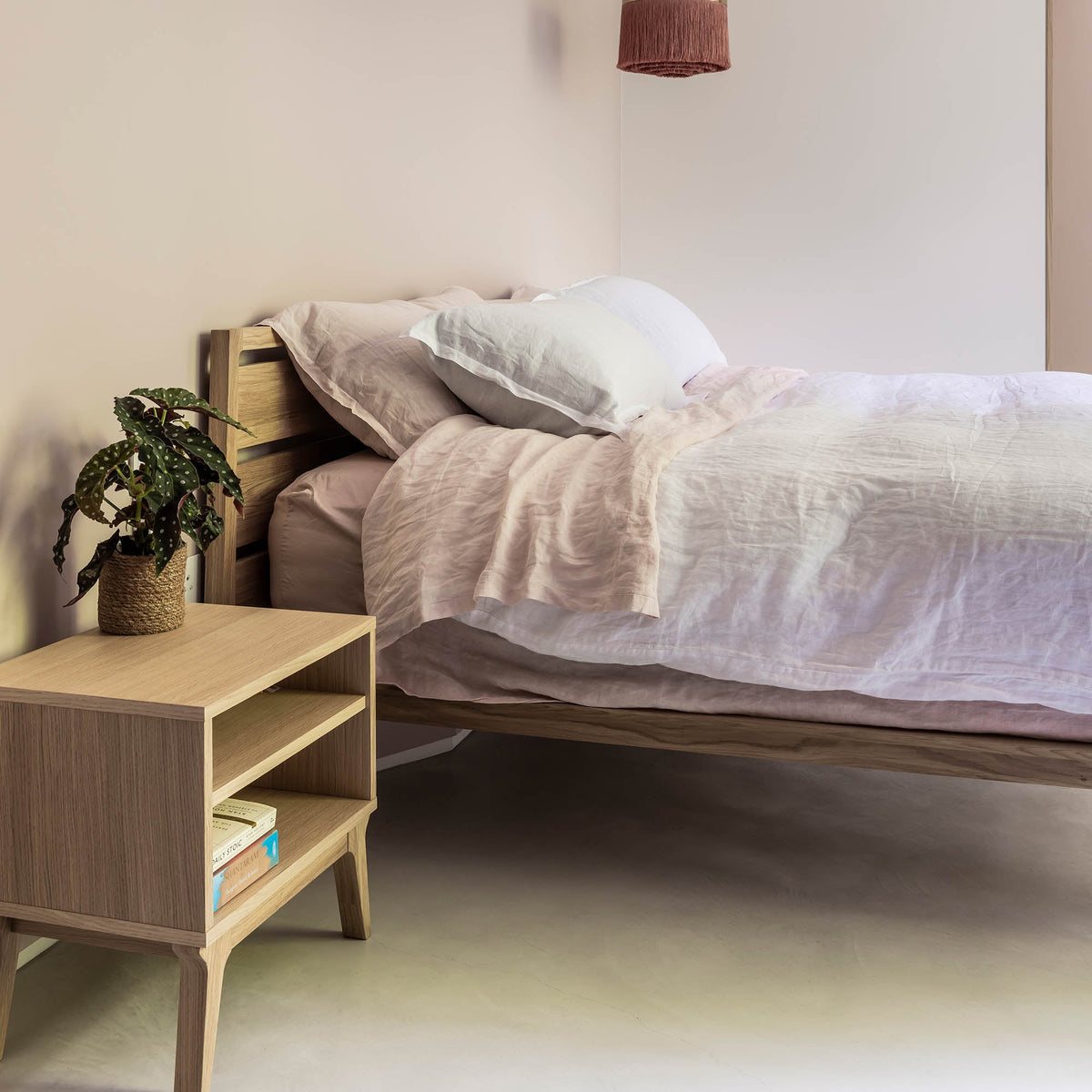 Case Valentine Bedside Table in Oak with a plant, styled in a bedroom, solid oak and oak veneer