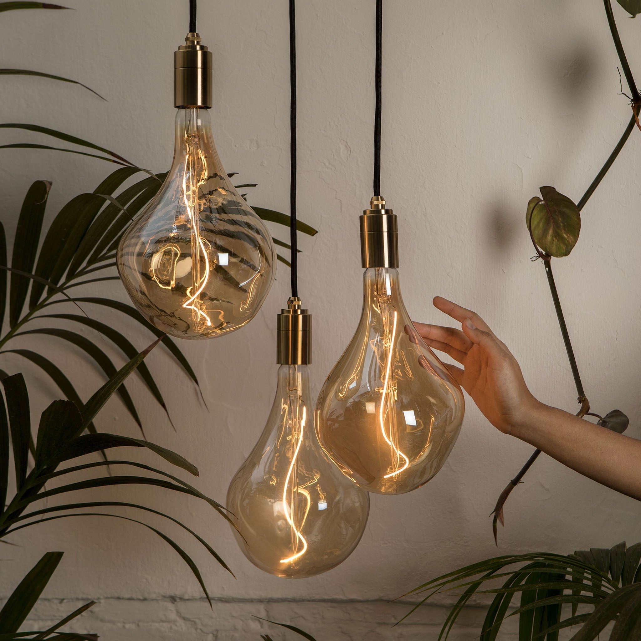 Tala Triple Pendant in Brass with Voronoi II bulbs — lifestyle with hand for scale